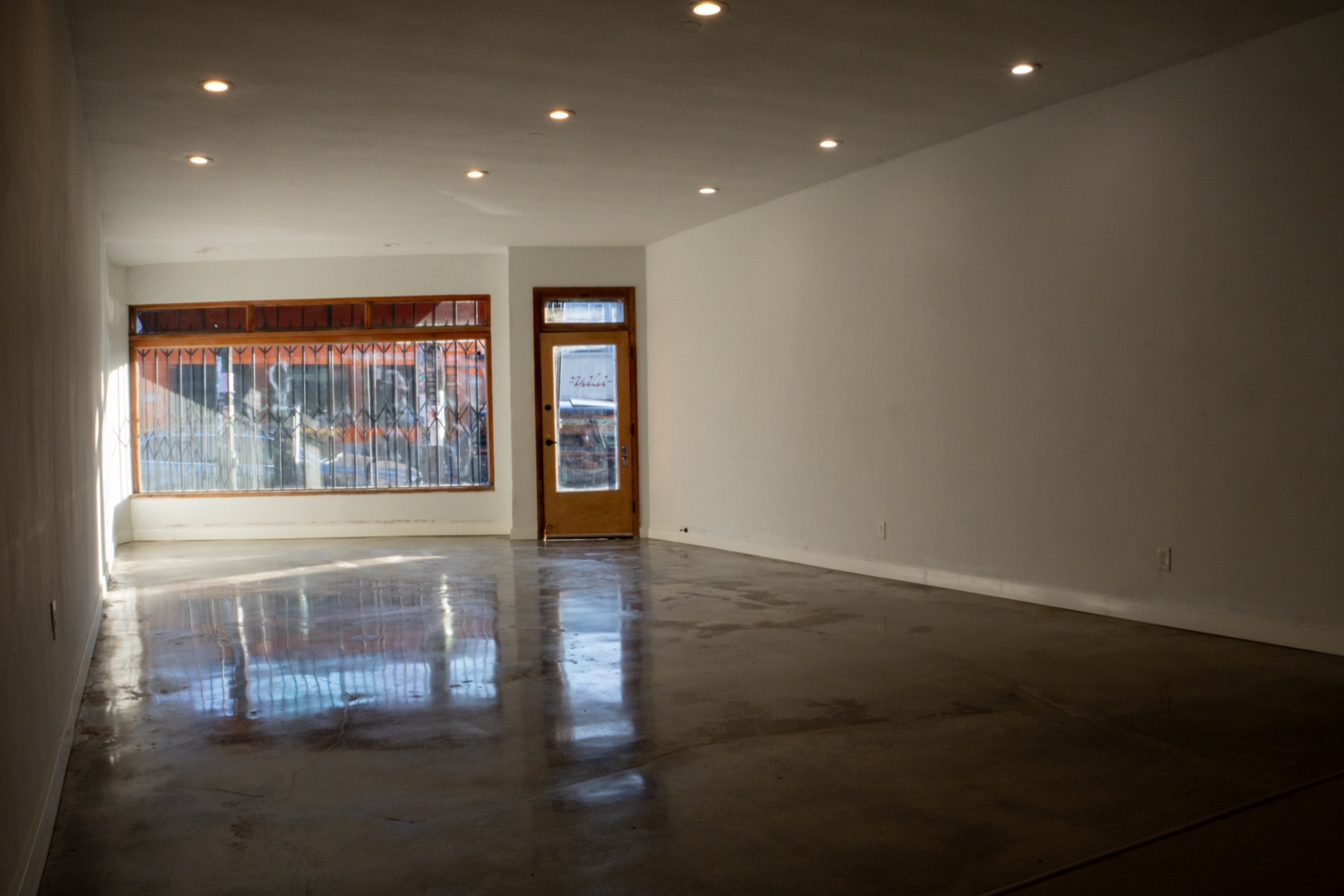 The vacant 3815 W. Sunset Blvd. interior looking toward the storefront, with the display window and timber entry door at the left.